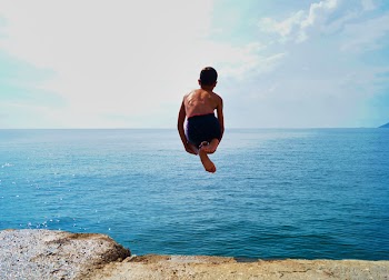 Time Lapse Photography of Boy in Black Shorts Jumping on Body of Water