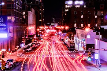 time lapse photography of cars on road between buildings at night time