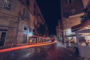 timelapse photograhy of orange light and group of people sitting on patio set beside commercial buildings during nighttime