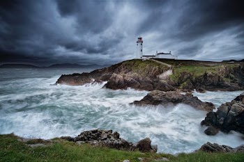 timelapse photograph of lighthouse on cliff near beach