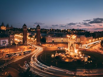 timelapse photography of lighted buildings and vehicles on road under clear blue sky