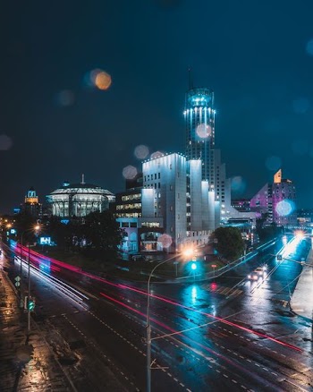 timelapse photography of vehicle passing on road in front of white and gray concrete building