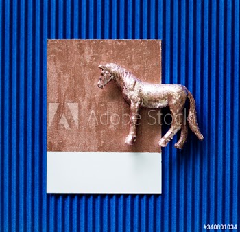Tiny metallic horse on blue paper