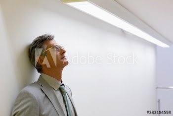 Tired mature corporate businessman leaning against wall