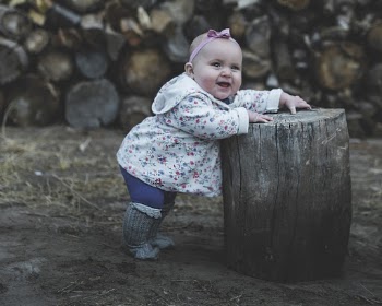 Toddler Standing and Leaning Against Log