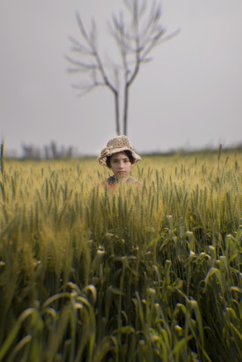 Toddler Wearing Brown Hat in the Middle of Green Field