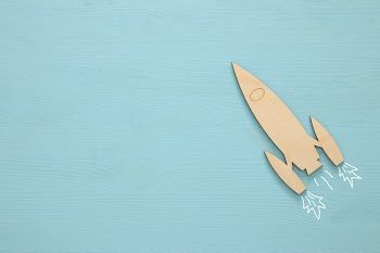 Top view image of wooden rocket toy over pastel background