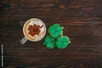 top view of cappuccino and cookies in shape of shamrocks on wooden table
