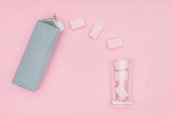 Top view of marshmallows, glass and carton package isolated on pink
