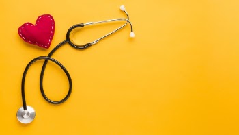 Top view of stitched heart shape with stethoscope against bright yellow background Free Photo