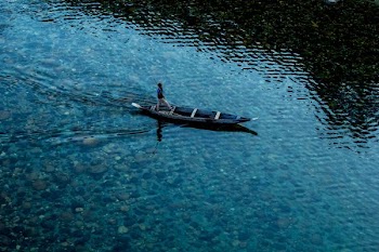 top view photo of man riding wooden boat on calm body of water