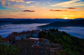 top view photography of village on top of hill covered with clouds under yellow skies