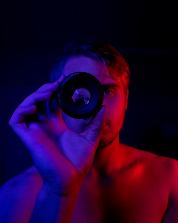 Topless Man Holding Round Black Mirror Device