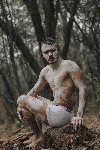 Topless Man in White Shorts Sitting on Brown Tree Branch
