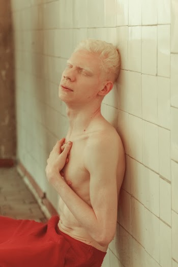 Topless Man Leaning on Tile Wall