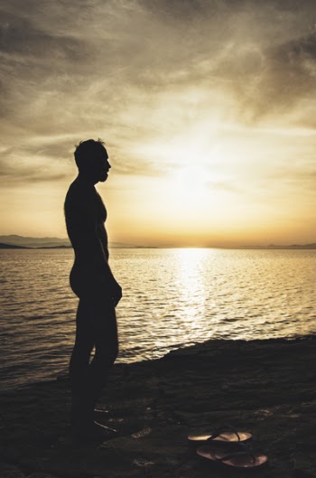 Topless Man on Sand Near Body of Water during Sunset
