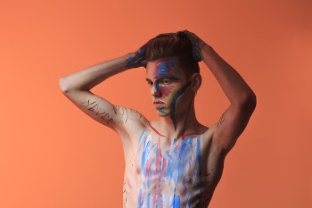 Topless Man Posing With Blue and Red Paint on His Body
