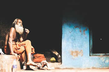 Topless Man Sitting Beside Blue Painted Wall