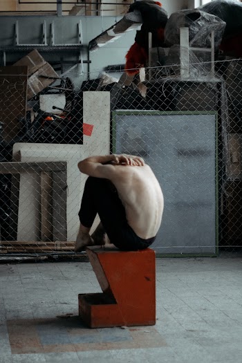 Topless Man Sitting on Brown and Black Block
