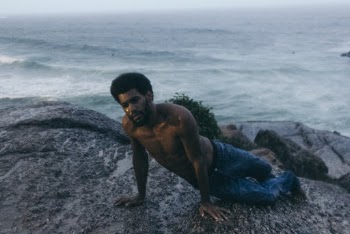 Topless Man Sitting on Rock