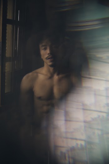 Topless Man Standing Beside Window