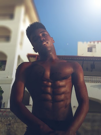 Topless Man Standing Near White Building