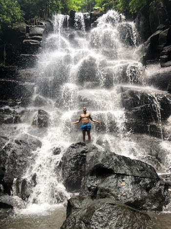 Topless Man Standing on a  Rock at the Center of a Cascade