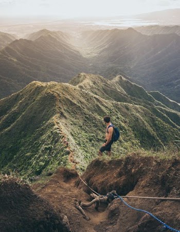 topless man with blue backpack on top of mountain