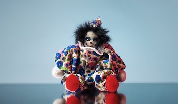 Toy Clown Doll Sits On Mirror