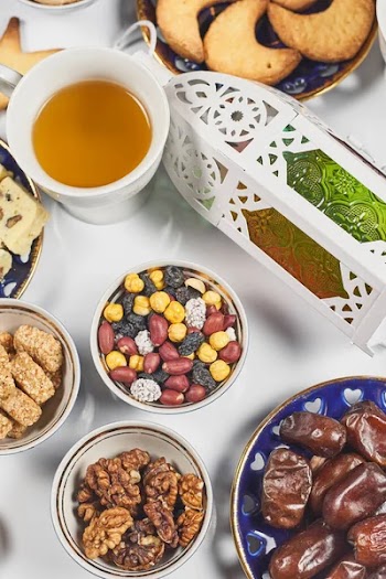 Traditional Ramadan dinner on pure white table. Traditional middle-eastern lunch with cookies and sweets. Ramazan Iftar food - meal Muslims eat after sunset during Ramadan. Top view