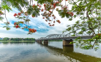 Trang Tien Bridge looming flamboyant side branches reflecting on the river. This is a classic photo corners symbol of Hue