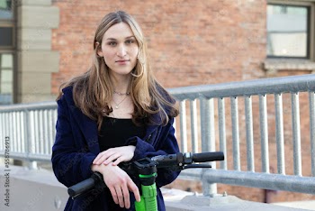 Trans woman outside with an electric scooter.