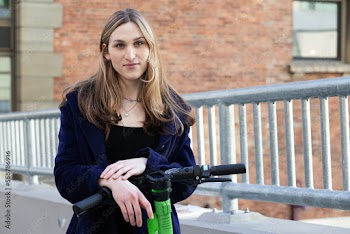 Trans woman outside with an electric scooter.