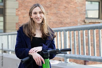 Trans woman outside with an electric scooter.