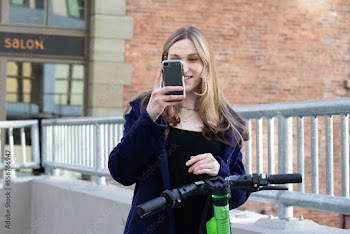 Trans woman outside with an electric scooter.