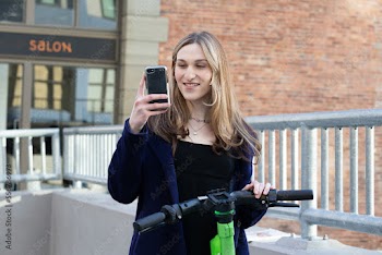 Trans woman outside with an electric scooter.