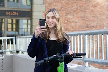 Trans woman outside with an electric scooter.