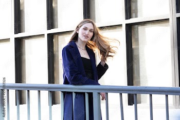 Trans woman posing next to a railing.