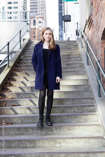 Trans woman posing on stairs outside.