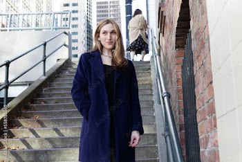 Trans woman posing on stairs outside.