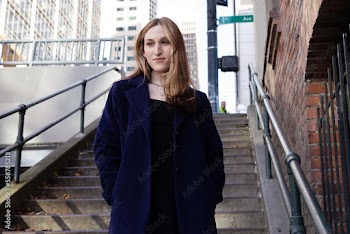 Trans woman posing on stairs outside.