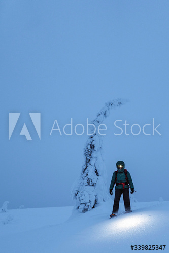 Trekker with a headlamp walking in a snowy Riisitunturi National Park, Finland