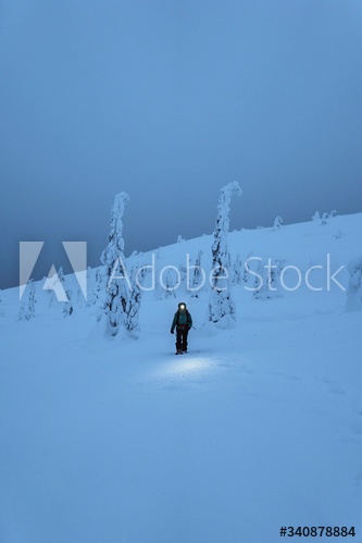 Trekker with a headlamp walking in a snowy Riisitunturi National Park, Finland