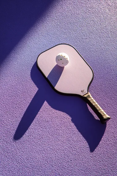 Trendy Pickleball Paddle and Ball on Lavender Surface Trendy Pickleball Paddle and Ball on Lavender Surface