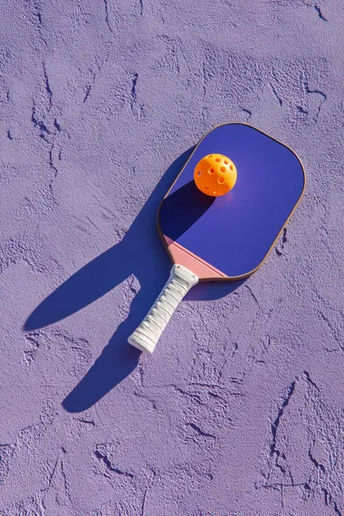 Trendy Pickleball Paddle and Ball on Lavender Surface Trendy Pickleball Paddle and Ball on Lavender Surface