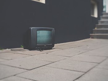 turned off black CRT TV near black concrete wall