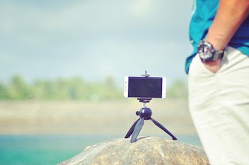 Turned Off White Android Smartphone With Mini Tri Stand on Rock
