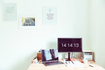 turned on flat screen computer monitor beside laptop computer on brown wooden surface