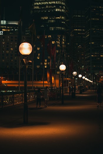 Turned On Lamp Posts Beside High-rise Buildings At Night