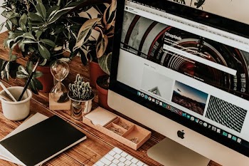 turned-on silver iMac on brown wooden surface